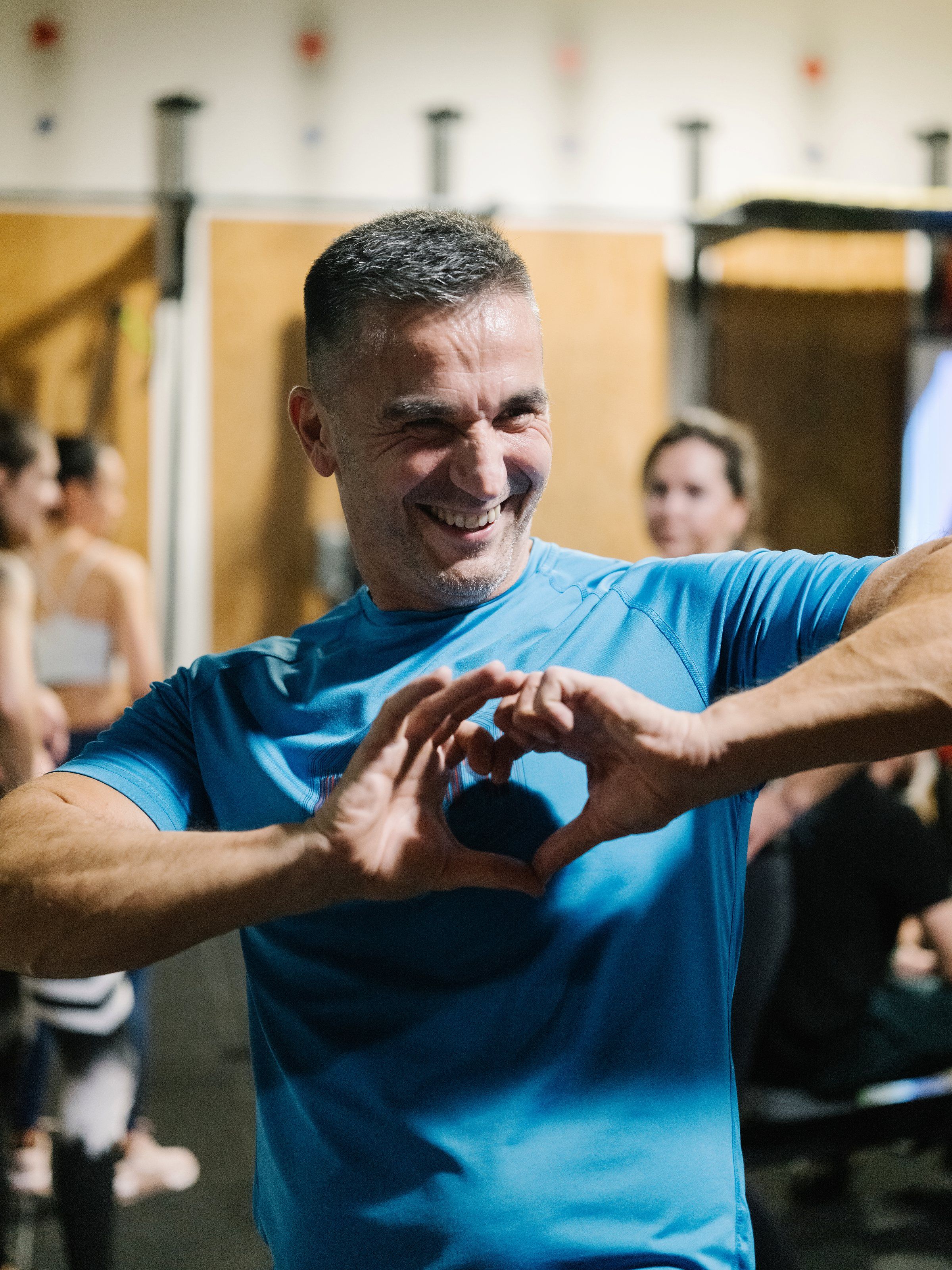 Uśmiechnięty klubowicz układa dłonie w kształt serca podczas zajęć w CrossFit Wilanów