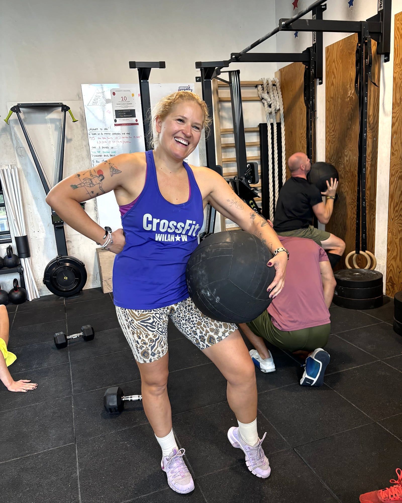 Uśmiechnięta klubowiczka z piłką lekarską na sali CrossFit Wilanów