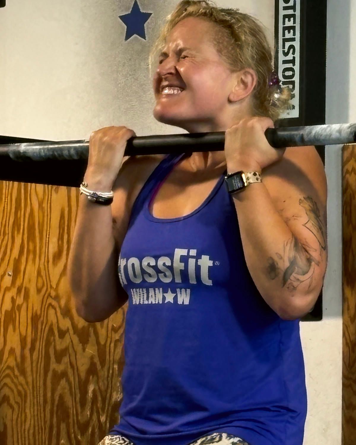 An athlete straining on the pull-up bar during a club competition